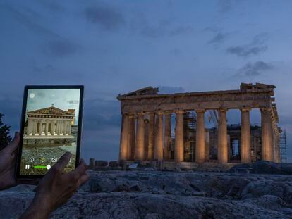 A man holds up a tablet showing a digitally overlayed virtual reconstruction of the ancient Parthenon temple, at the Acropolis Hill in Athens, Greece on Tuesday, June 13, 2023.