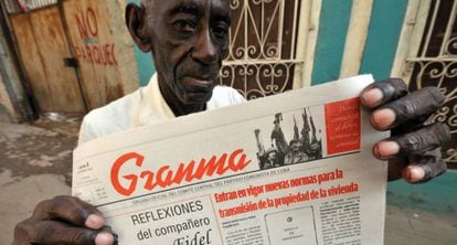 A Cuban man holds up a copy of state newspaper Granma.