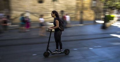 A young woman rides an electric scooter in Seville.