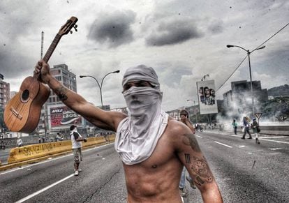 Artist Tomás Vivas, 29, holds up a traditional Venezuelan 'cuatro' instrument during a protest in Caracas.