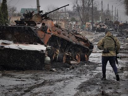 A Ukrainian soldier looks at a wrecked Russian tank during the first days of the invasion, in Bucha (Ukraine).