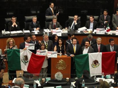 Leftist senators hold up Mexican flags to protest the energy reform during Tuesday’s debates.