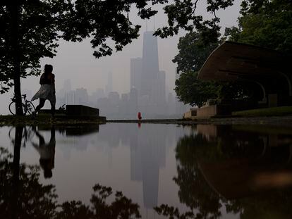 A person walks along the shore of Lake Michigan as the downtown skyline is blanketed in haze from Canadian wildfires on June 27, 2023, in Chicago.