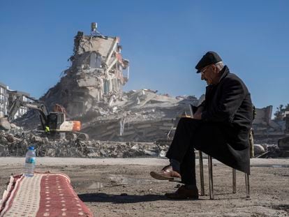 A man waits next to machines removing rubble from a building in Nurdagi where his relatives were trapped, on February 9.