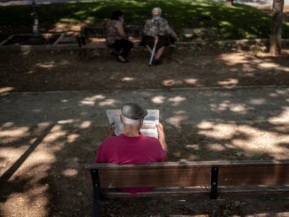 An elderly person reading a newspaper in the park.