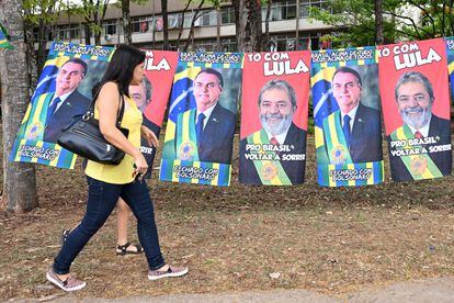 A woman walks past towels with the images of former Brazilian president and presidential candidate for the leftist Workers' Party, Luiz Inácio Lula da Silva, and Brazilian President Jair Bolsonaro, in Brasilia.