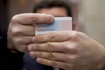 The first Turkish citizen granted political asylum in Spain shows his refugee ID card.