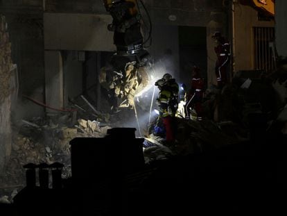 Emergency service personnel watch as an excavator moves rubble at 'rue Tivoli' after a building collapsed in the street, in Marseille, southern France, on April 9, 2023