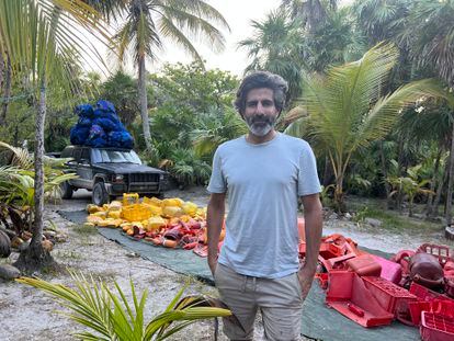 Alejandro Durán poses next to piles of garbage collected from the beaches of Tulum.