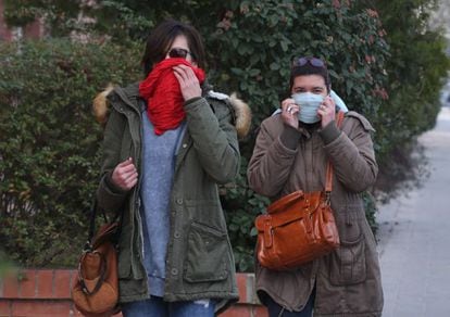 Two women cover their mouths on a street in Igualada.