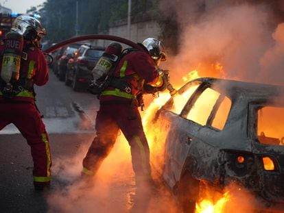 Firefighter extinguish a burning vehicle destroyed by protesters in Nanterre, west of Paris, late on June 27, 2023.