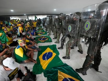 Supporters of Brazil's former President Jair Bolsonaro, sit in front of police inside the Planalto Palace after storming it, in Brasilia, January 8, 2023.