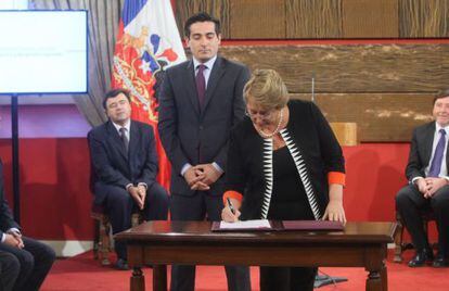 Bachelet signs a presidential decree under the watchful gaze of Pe&ntilde;ailillo.