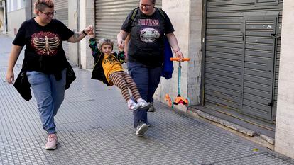 Anastasia Domini, left, and her wife Anna, swing their daughter Una as they walk to a park in Buenos Aires, Argentina, on April 22, 2023.
