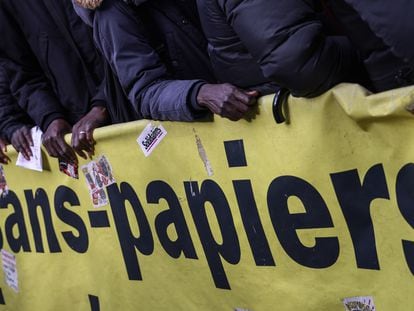 Protesters and migrants stand next to a part of banner reading 'without paper' during a demonstration against a proposed new immigration law, in front of the Senate in Paris, France, November 06, 2023.