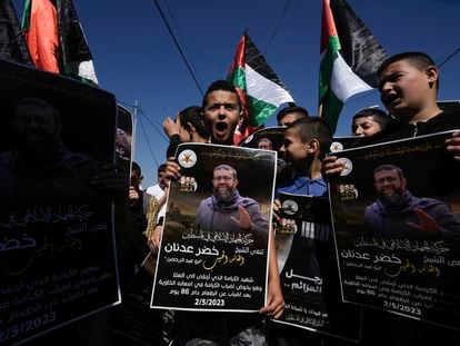 Palestinian kids hold posters showing Khader Adnan, a Palestinian Islamic Jihad militant who died in Israeli prison after a nearly three-month hunger strike, in the West Bank village of Arrabe, on May 2, 2023.