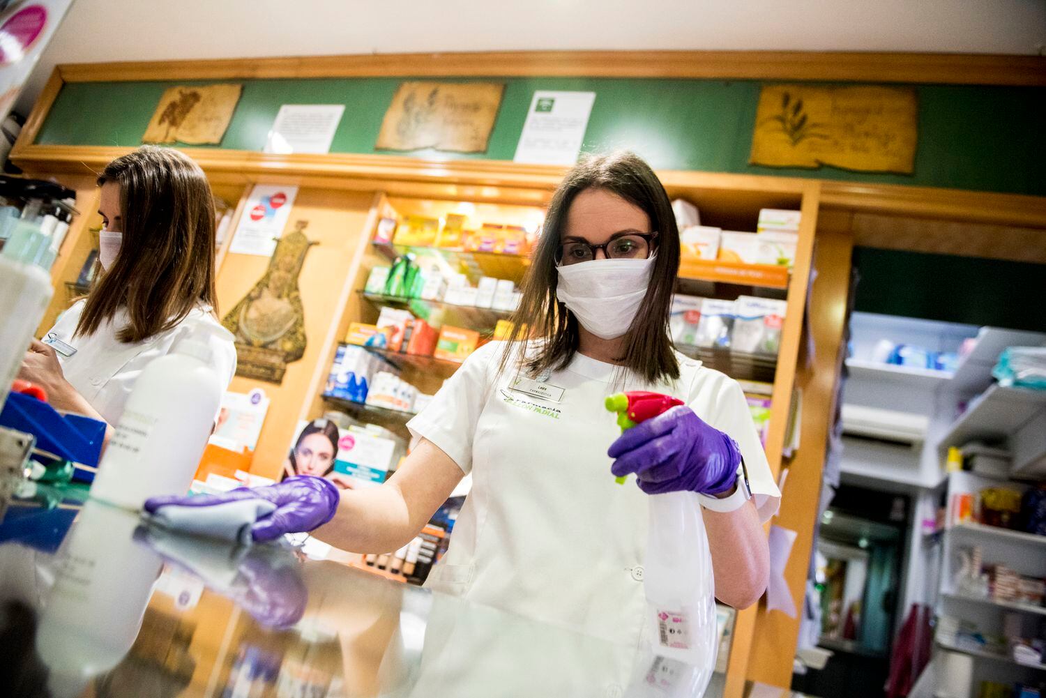 A pharmacist disinfects a counter in Granada.