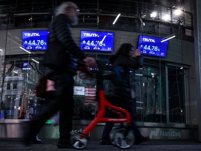 People walk past screens displaying trading information about shares of Truth. Social and Trump Media & Technology Group, outside the Nasdaq Market site in New York City, U.S., March 26, 2024.