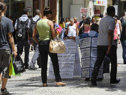 A black woman looks at job advertisements in a São Paulo street.