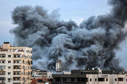 A plume of smoke rises over some buildings attacked by Israel in Gaza.