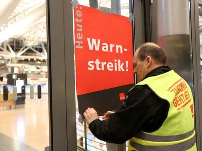An airport security union representative posts a poster reading "Warning strike!" in an empty Terminal 2 at Hamburg Airport