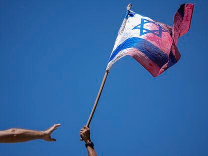 A demonstrator waves a colored Israeli flag during a protest against plans by Prime Minister Benjamin Netanyahu's government to overhaul the judicial system, outside the Knesset, Israel's parliament, in Jerusalem, Monday, July 24, 2023.