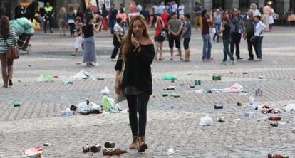 A passer-by navigates the beer bottles and other trash left behind by soccer fans in Madrid's Plaza Mayor.