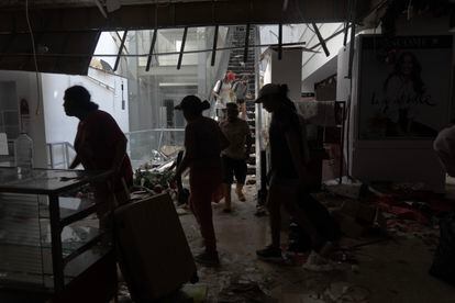 People take items from a supermarket looted after Hurricane Otis.