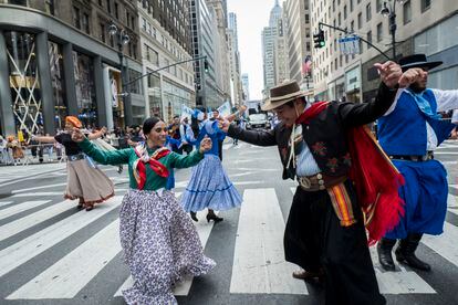 Marchers dance together down New York's 5th Avenue in traditional costumes during the 55th Hispanic Day Parade, on October 13, 2019.