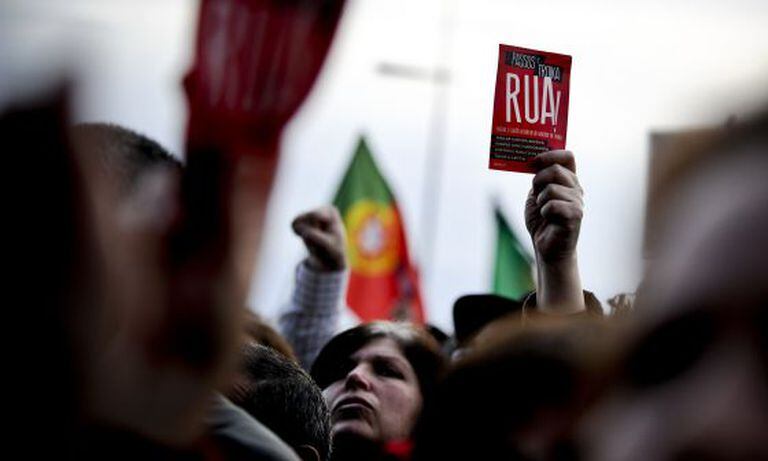 A woman brandishes a leaflet saying "Passos Troika Out!" during Saturday's march in Lisbon.
