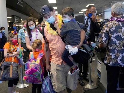 Hawaii resident Ryan Sidlow carries his son as their family boards a United Airlines flight to Hawaii at San Francisco International Airport in October 2020.