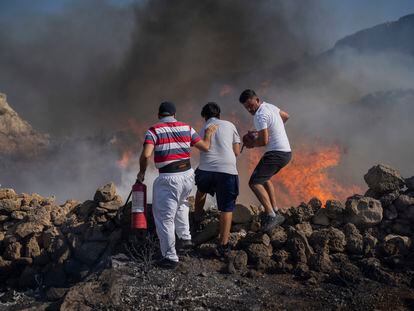 Local residents try to extinguish a fire, near the seaside resort of Lindos, on the Aegean Sea island of Rhodes, southeastern Greece, on July 24, 2023
