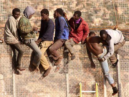 The sub-Saharan migrants perch on the border fence in Melilla on Thursday.