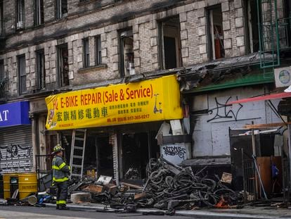 A firefighter looks through debris in the aftermath of a fire which authorities say started at an e-bike shop and spread to upper-floor apartments, Tuesday June 20, 2023, in New York.