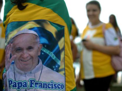A young pilgrim wrapped in a Brazilian flag with an image of Pope Francis speaks with mates in Rio de Janeiro.