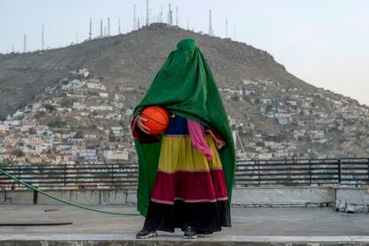 An Afghan woman poses with a basketball in Kabul, Afghanistan. Women's team sports have been banned under the Taliban. Even the captain of the women's wheelchair basketball team has had to take refuge in Spain.