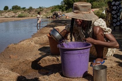 Marizeeti vierte en un cubo el agua que está recogiendo con un cuenco de un hoyo cavado en la orilla del río en Betoko, Madagascar.