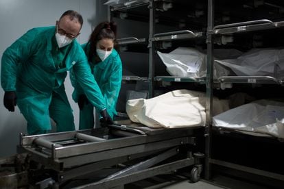 Funeral workers prepare to transfer a body to a coffin in Barcelona.