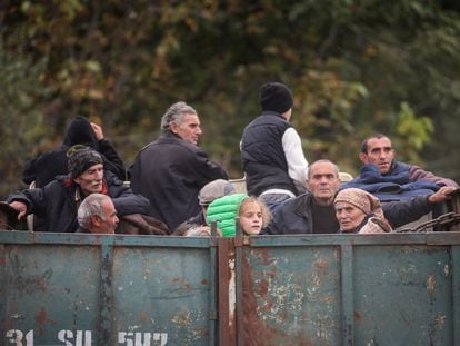 Refugees from the Nagorno-Karabakh region ride on the back of a truck as they arrive at the border village of Kornidzor, Armenia, on September 26, 2023.