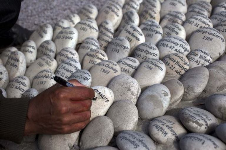 Simeon Irrazabal writes the name of his father, who he said was killed by the Peruvian army in 1987, at the "Ojo que Llora" or "Eye that Cries" memorial in Lima, Peru, Wednesday, Aug. 28, 2013.