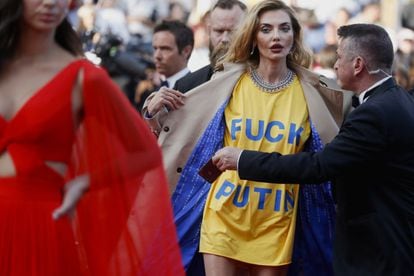 A protester with a message against Vladimir Putin attempts to join the red carpet before the screening of 'The Old Oak.'