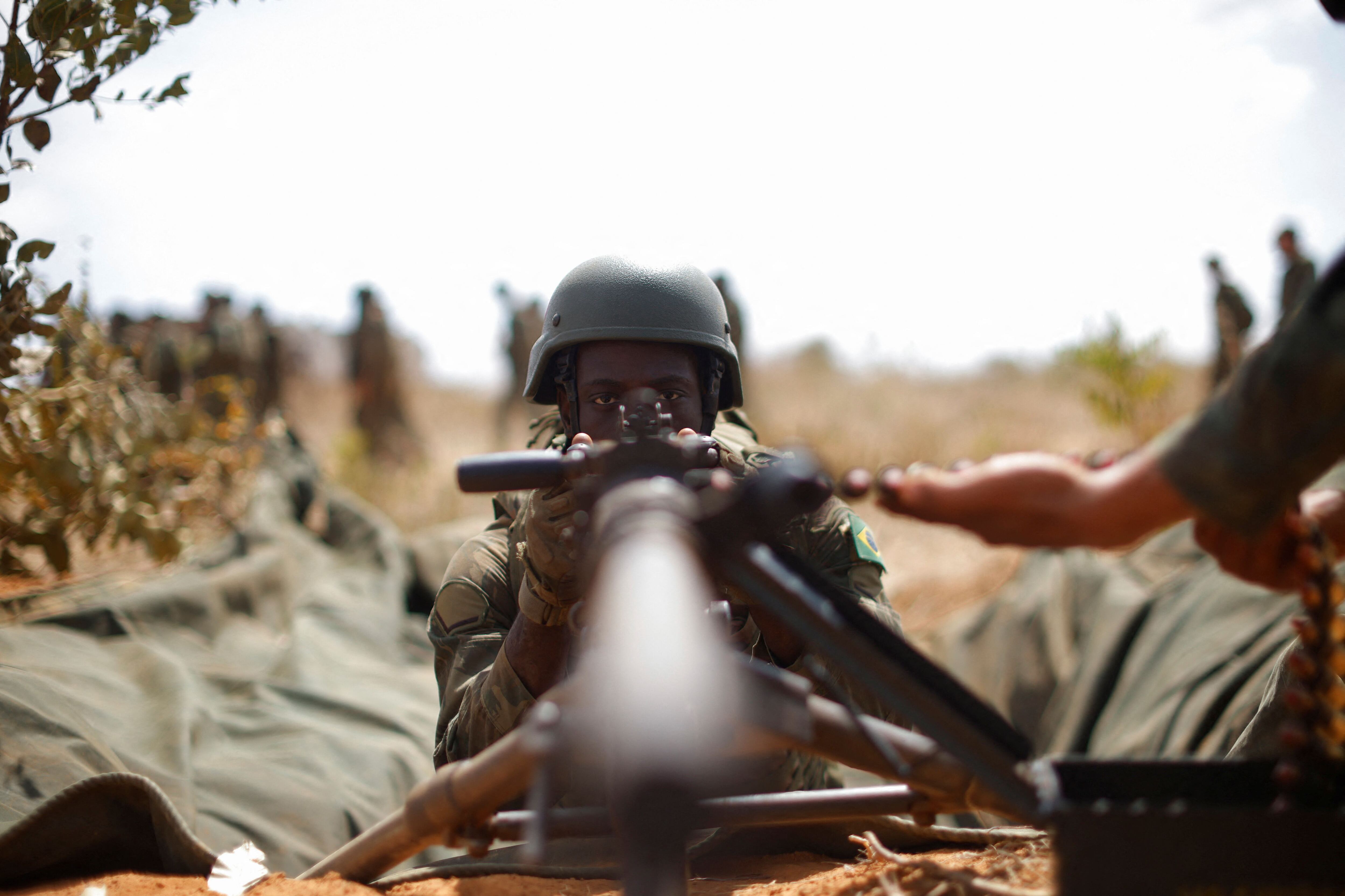A Brazilian soldier aims a machine gun.