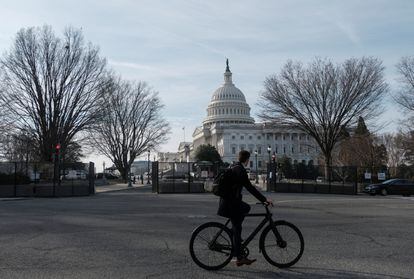 A bicyclist rides past the US Capitol building, surrounded by temporary anti-riot fencing installed around its perimeter, on the day of US President Joe Biden's State of the Union address.