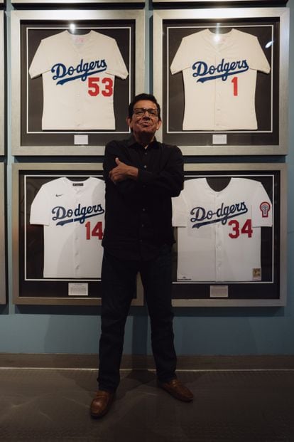 The pitcher poses with his #34 jersey, hanging next to those of Pee Don Drysdale (#53), Wee Reese (#1) and Gil Hodges (#14).