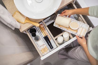 A woman tidying up a bathroom drawer. The new minimalist organization philosophies have gained followers and have spread from the home interiors to every aspect of our lives.