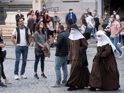 Two masked nuns walk by a group of tourists in Seville on Monday.