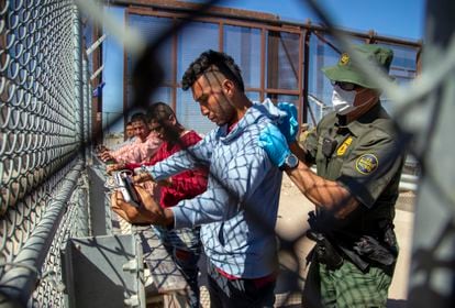 Migrants are pat down by a Border Patrol agent as they enter into El Paso, Texas