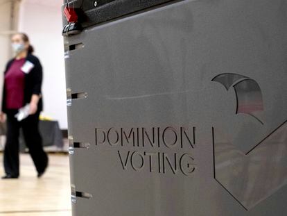 A worker passes a Dominion Voting ballot scanner while setting up a polling location at an elementary school in Gwinnett County, Georgia, on January 4, 2021.