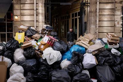 A man walks past uncollected garbage in Paris, Wednesday, March 15, 2023 as sanitation workers are on strike. 