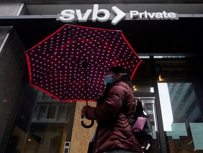 A pedestrian carries an umbrella while walking past a Silicon Valley Bank Private branch in San Francisco, Tuesday, March 14, 2023.